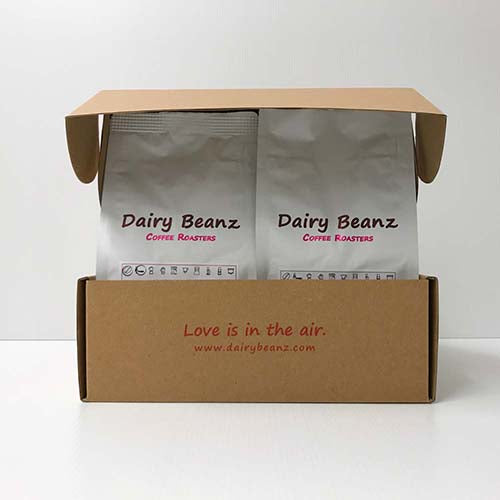 Two bags of coffee in a gift box with the text "Love is in the air" and Dairy Beanz web address www.dairybeanz.co.nz, part of the Custom Coffee Gift Pack with a personalized label.