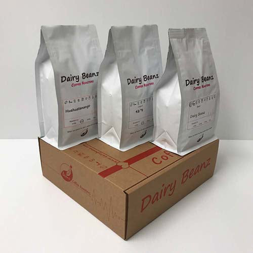 Three bags of coffee sitting on top of the 3 Roast Coffee Gift Pack gift box, perfect for coffee enthusiasts.