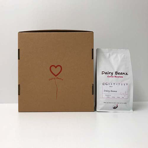 One bag of coffee placed beside the 3 Roast Coffee Gift Pack gift box, showing off the packaging.